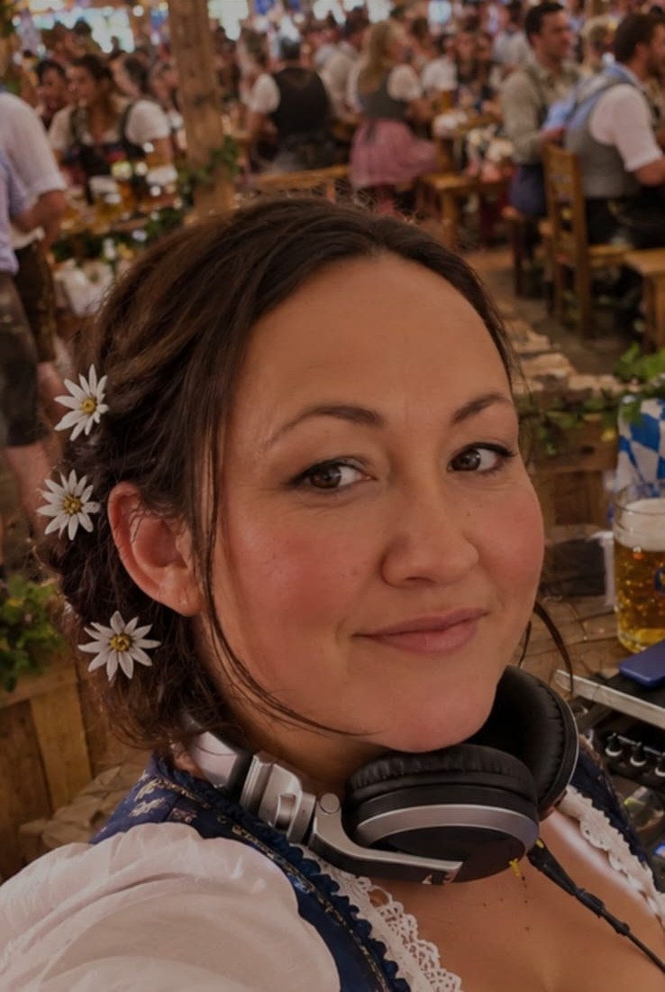 DJ Melli im Dirndl mit Kopfhörern am DJ-Pult in einem Festzelt